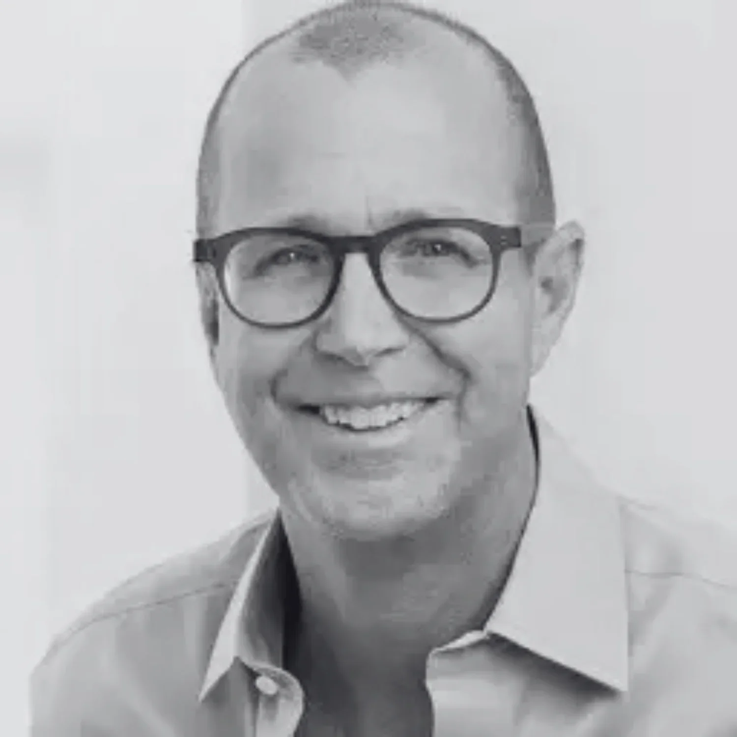 Black and white photo of Alan Murray smiling at the camera, wearing a collared shirt.
