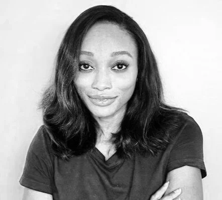 Stephanie Kuku wearing a black t-shirt, looking at the camera with a slight smile.